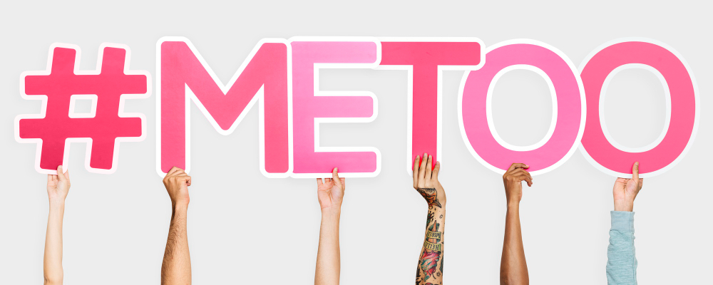 Pessoas segurando placas de hashtag formando a frase “#metoo”